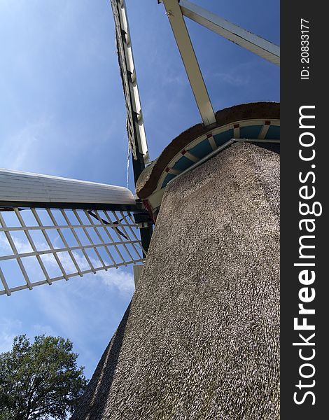 Low point of view picture from a typical Dutch windmill. The body and wingsare set against a blue sky with light clouds. Low point of view picture from a typical Dutch windmill. The body and wingsare set against a blue sky with light clouds.