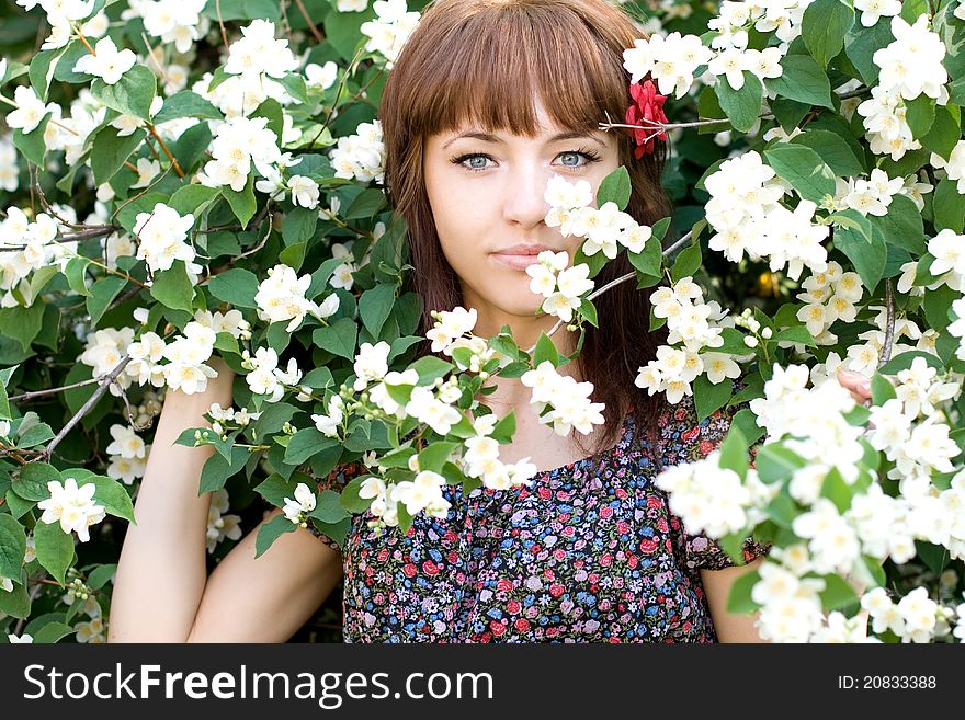 Closeup portrait of a beautiful girl standing among flowers