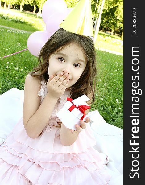 Little girl outdoors celebrating birthday is happy and holding a gift box. Little girl outdoors celebrating birthday is happy and holding a gift box.