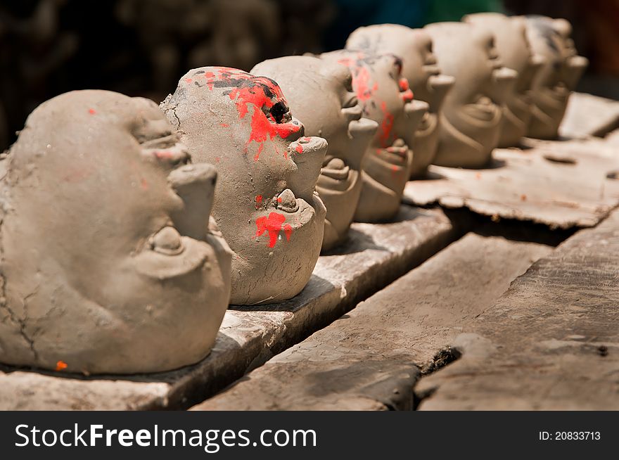 Clay heads of Goddesses and demons in a row are kept for drying in sunlight. Clay heads of Goddesses and demons in a row are kept for drying in sunlight