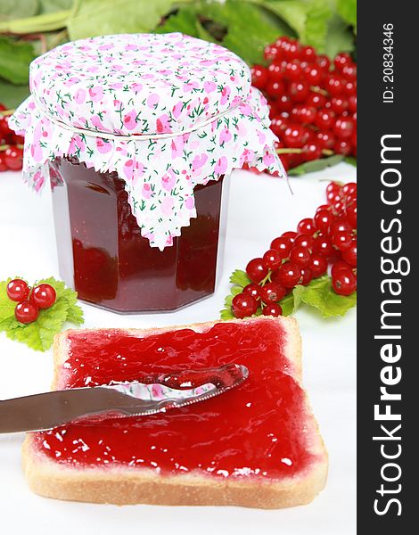 One glass of homemade red currant jam with fresh fruits, leaves and toast