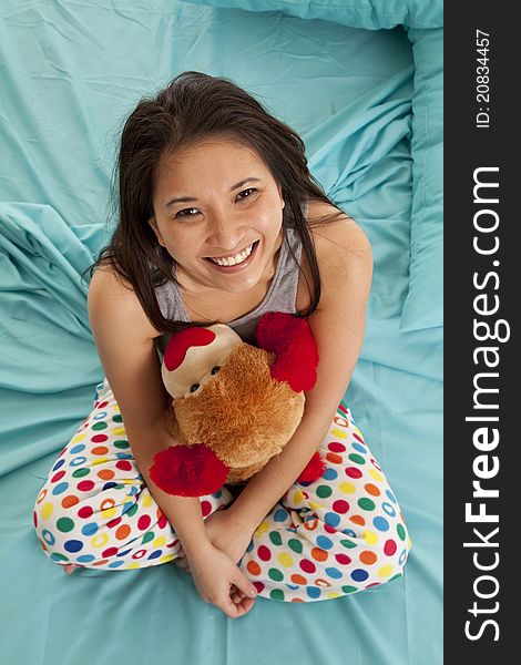 A woman looking up while she is in bed holding on to her stuffed animal. A woman looking up while she is in bed holding on to her stuffed animal