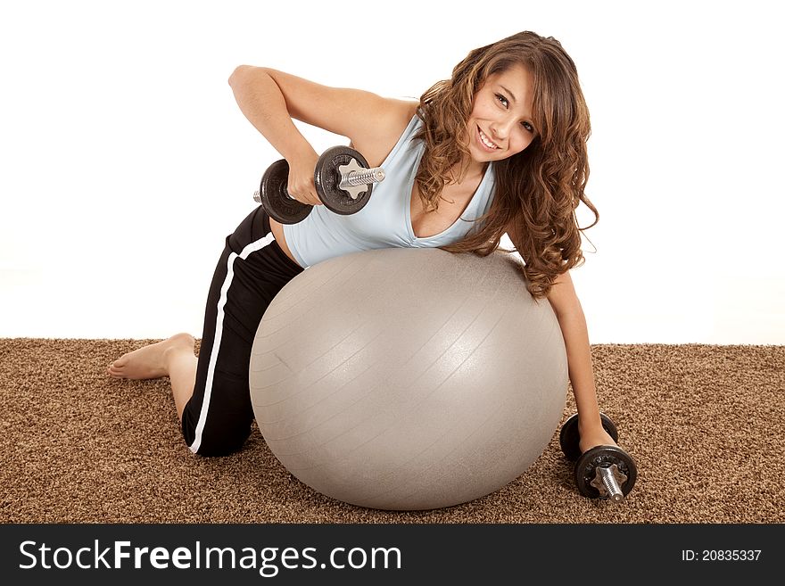 A woman working out with weights while she is laying on a exercise ball. A woman working out with weights while she is laying on a exercise ball.