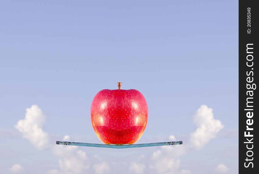 Red apple levitation on the glass ship an sky