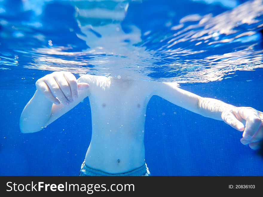 A young boy swimming in a clear pool. A young boy swimming in a clear pool