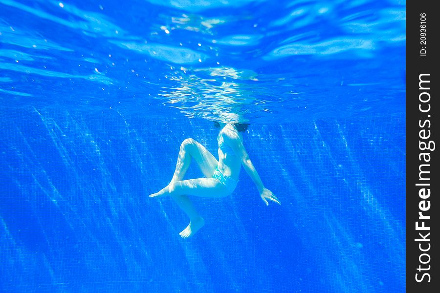 A young boy swimming in a clear pool. A young boy swimming in a clear pool