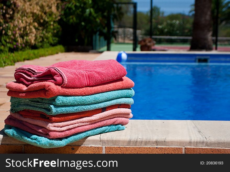 A pile of towels beside a beautiful pool. A pile of towels beside a beautiful pool