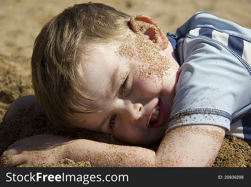Cute little boy lying in the sand on a beach. Cute little boy lying in the sand on a beach