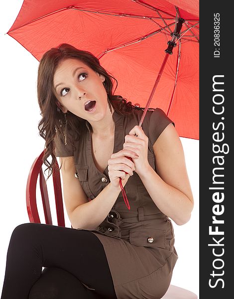 A woman sitting under a red umbrella with a shocked expression on her face. A woman sitting under a red umbrella with a shocked expression on her face.