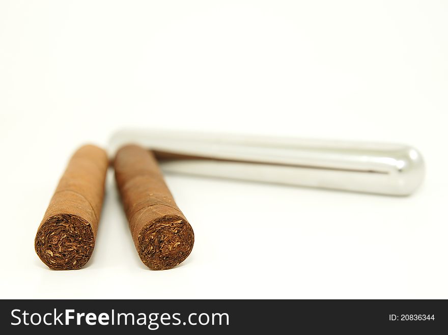 Close-up of two cigars and a stainless steel tube container. Close-up of two cigars and a stainless steel tube container