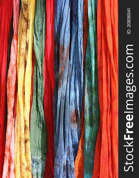 Colorful Scarves on sale at a market. They come in blue, red, green, yellow and pink.