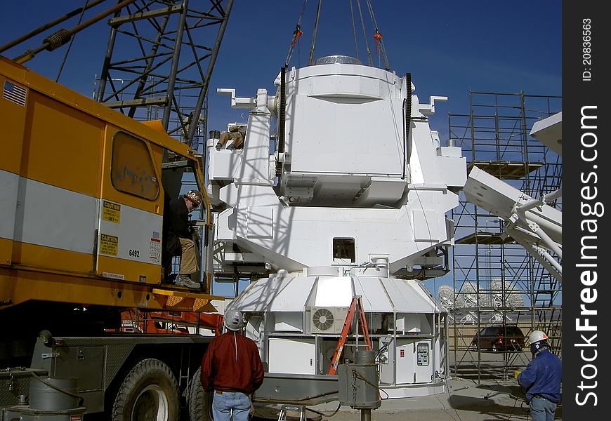 At the very large array located in new mexico, usa, a crane sets the base for a new radio astronomy observatory;. At the very large array located in new mexico, usa, a crane sets the base for a new radio astronomy observatory;