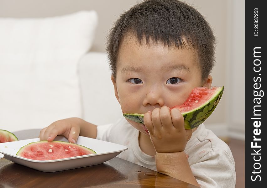 A cute baby is eating watermelon