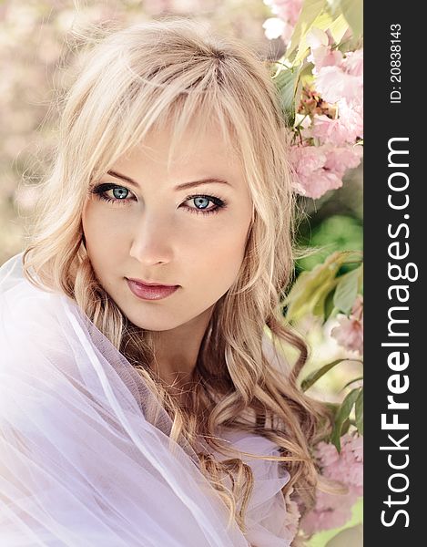 Portrait of beautiful girl with white kerchief and blooming sakura on background. Portrait of beautiful girl with white kerchief and blooming sakura on background