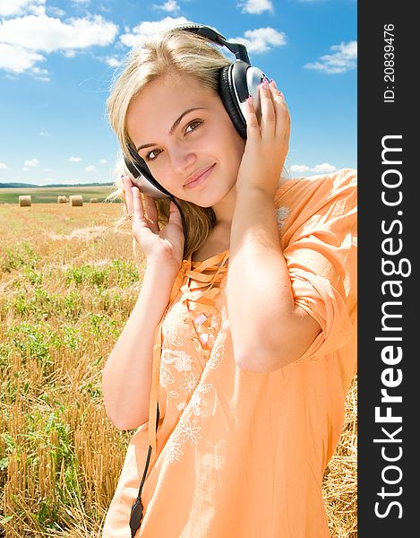 Girl at a stack of straw listening to music