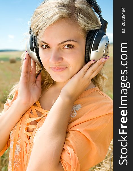 Girl at a stack of straw listening to music