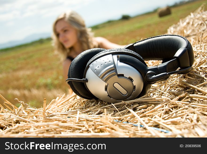 Girl at a stack of straw listening to music