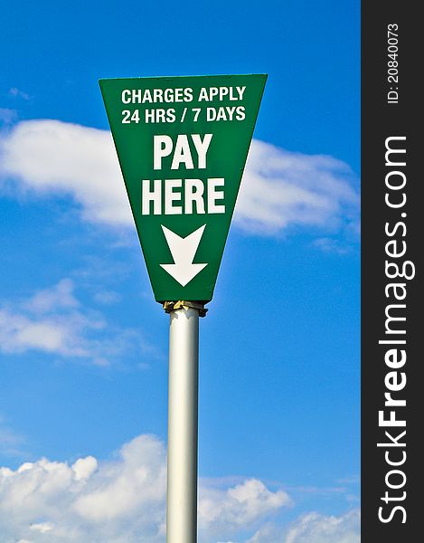 Green pay here sign with blue sky in background