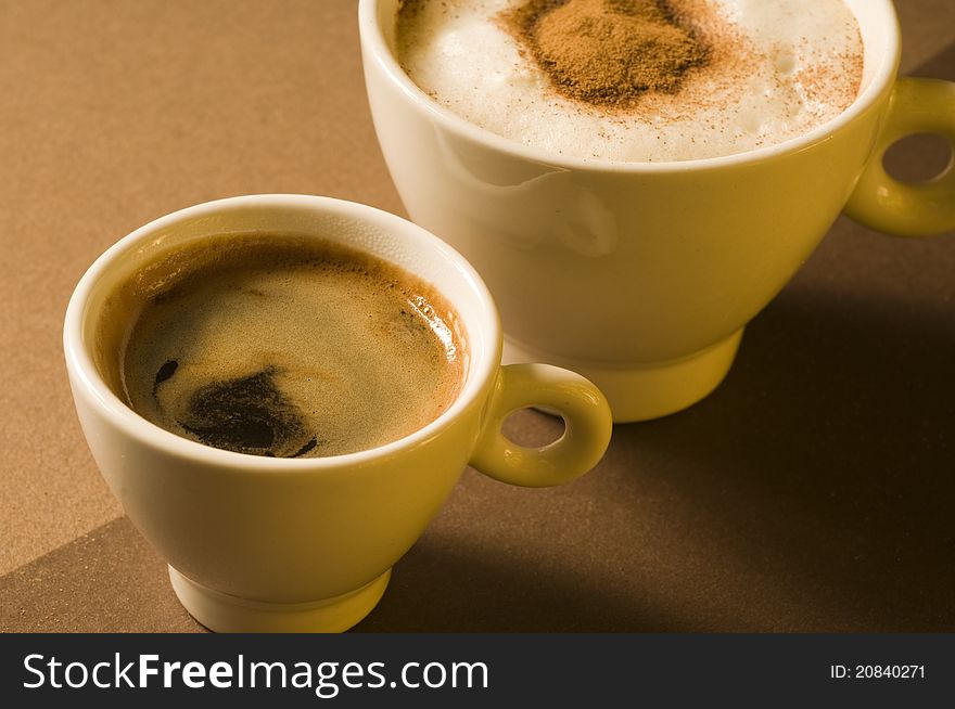 Two coffee cups with hot espresso and cappuccino over brown background. Two coffee cups with hot espresso and cappuccino over brown background