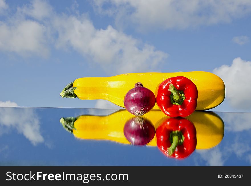 Summer vegetables on mirror and sky background