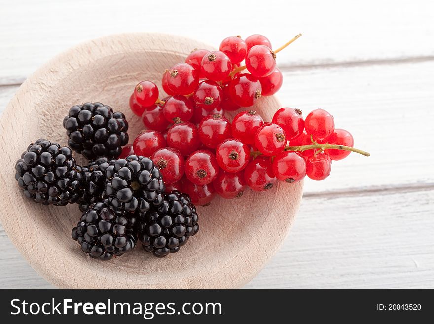 Blackberries and currants on a wooden white table