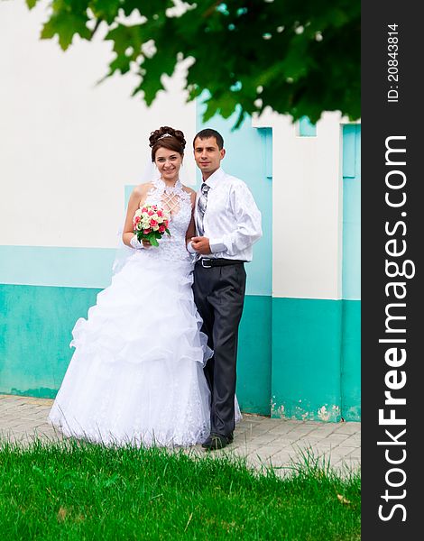 Happy bride and groom near the church wall