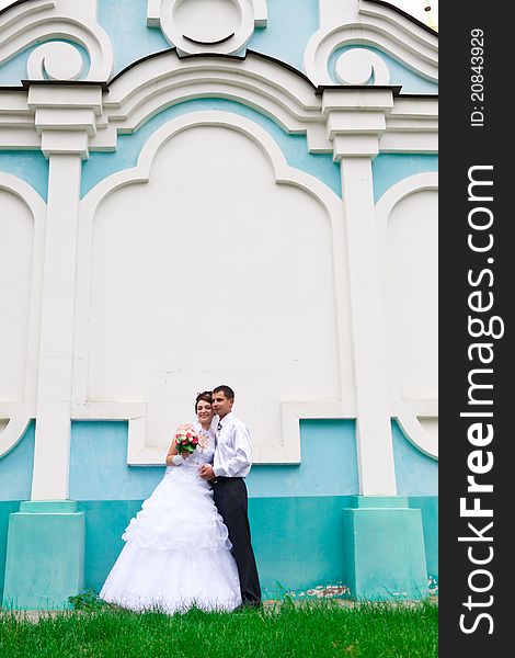 Happy bride and groom near the church wall