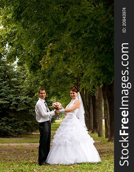 Happy bride and groom standing in the green alley