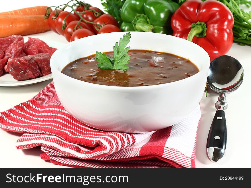 A bowl of goulash soup and fresh ingredients