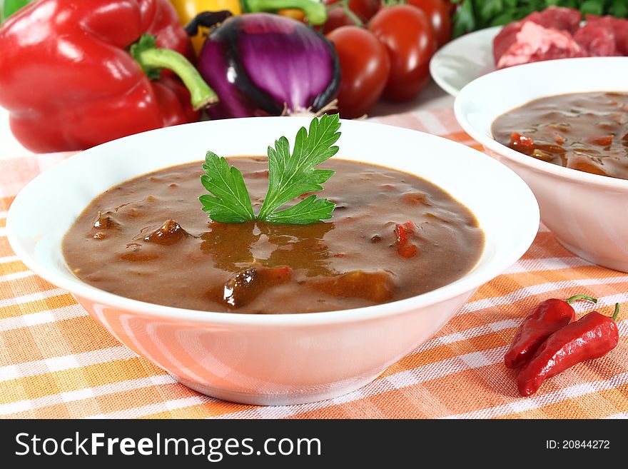 A bowl of goulash soup and fresh ingredients