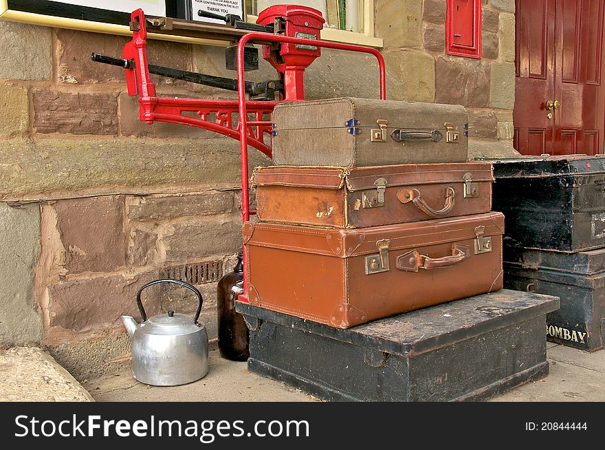 Old piled suitcases on a scale and a water kettle next to it. Old piled suitcases on a scale and a water kettle next to it