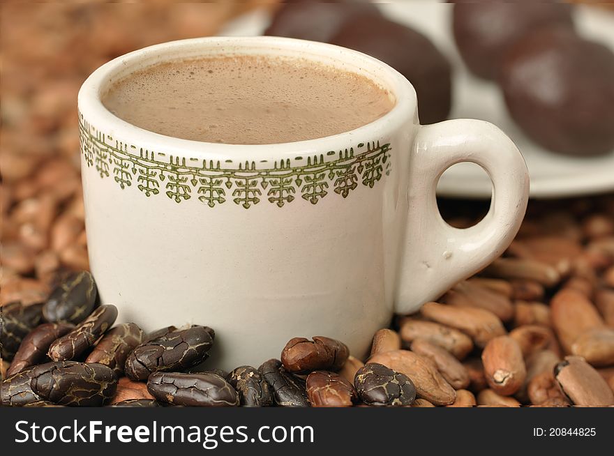 Cup of hot cocoa with raw cacao beans and chocolate balls
