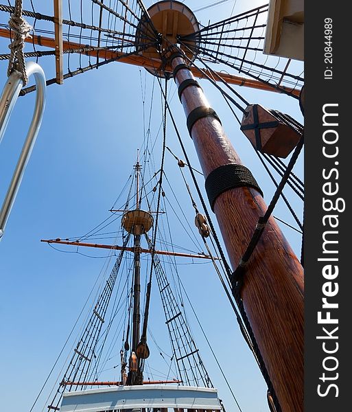 View of mast and rigging on the tall sail ship against the blue sky. View of mast and rigging on the tall sail ship against the blue sky.