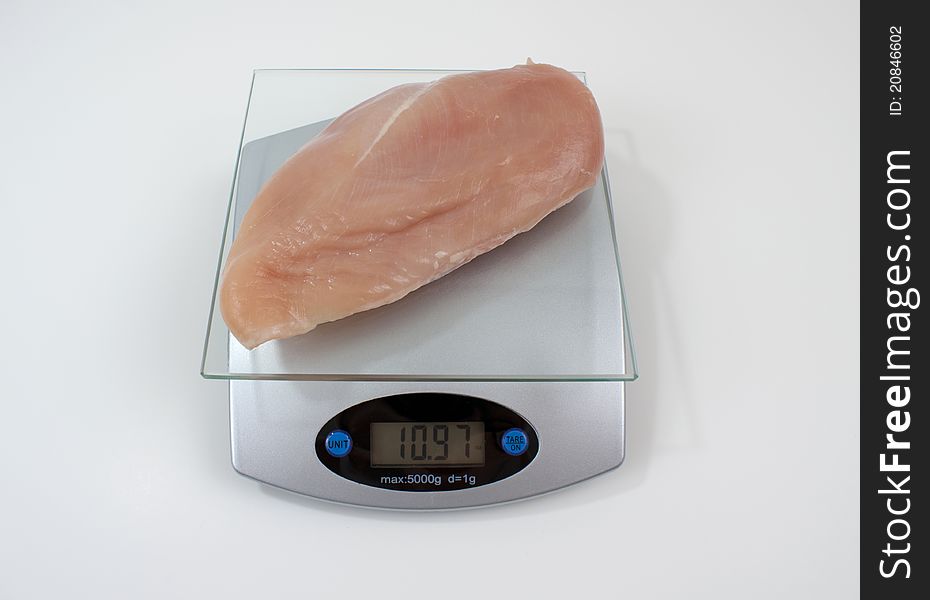 Boneless, skinless, chicken breast on weight scale. Boneless, skinless, chicken breast on weight scale