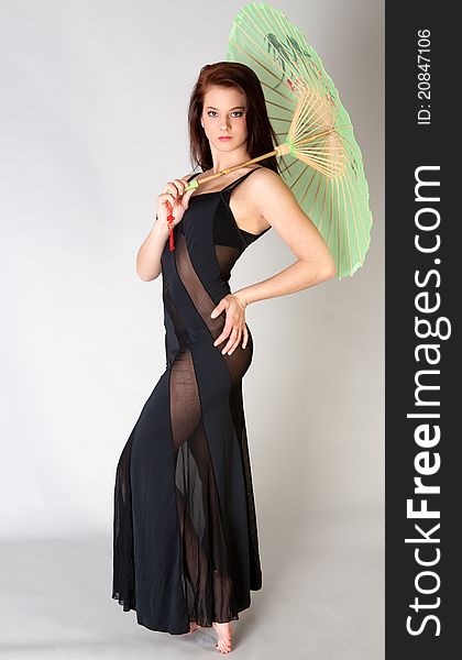 A portrait of a pretty young woman wearing a long black dress with sheer areas and holding a green parasol. A portrait of a pretty young woman wearing a long black dress with sheer areas and holding a green parasol