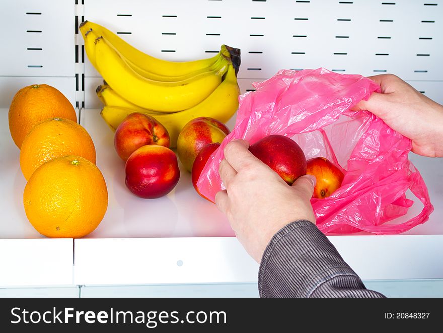 Hands take nectarines from a store shelves