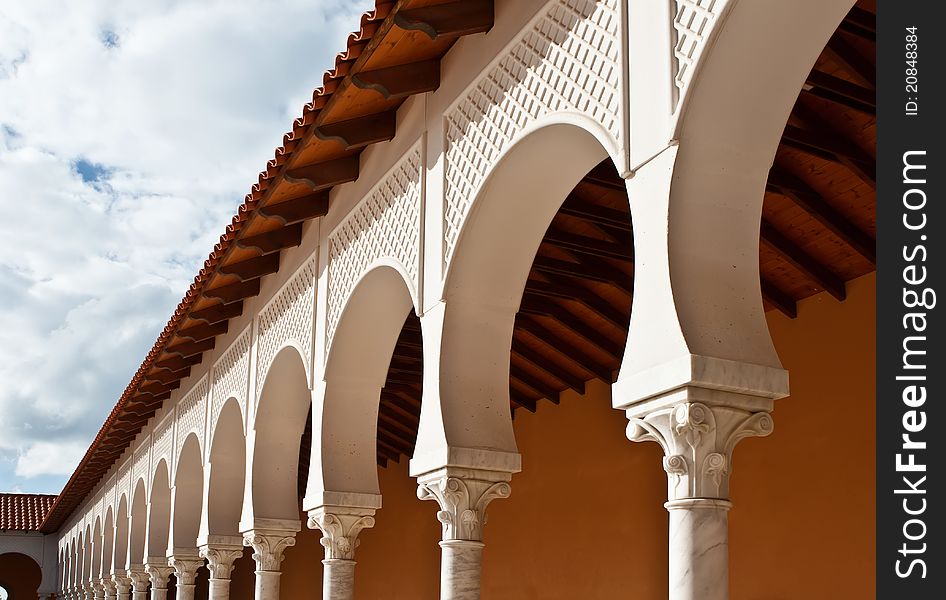 Pattern of a modern covered arcade with the tile roof on blue sky background.It is stylized to classical Spanish style. Caesarea, Israel. Pattern of a modern covered arcade with the tile roof on blue sky background.It is stylized to classical Spanish style. Caesarea, Israel.