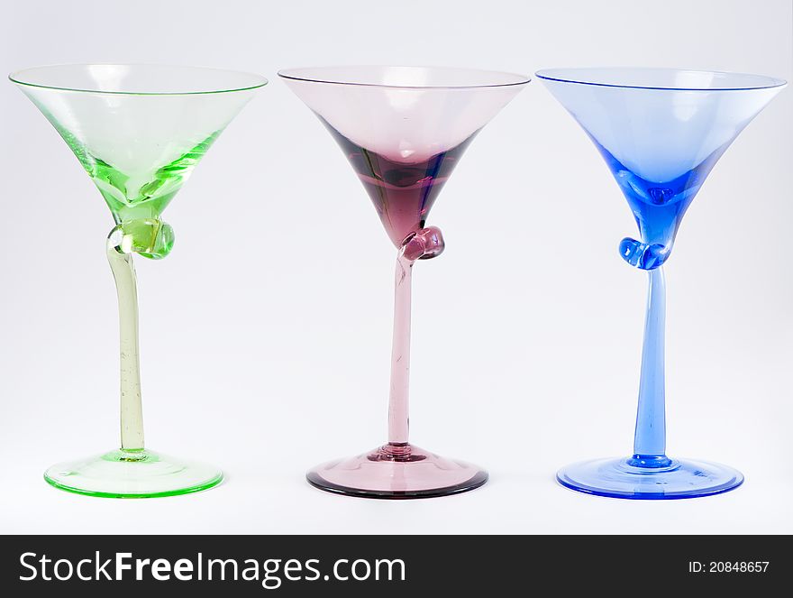 A row of three colorful cocktail glasses, green, red, blue.