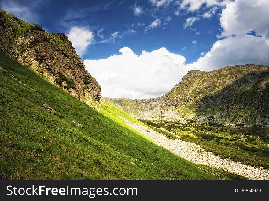 Mountain side with green grass and cloudy sky in summer