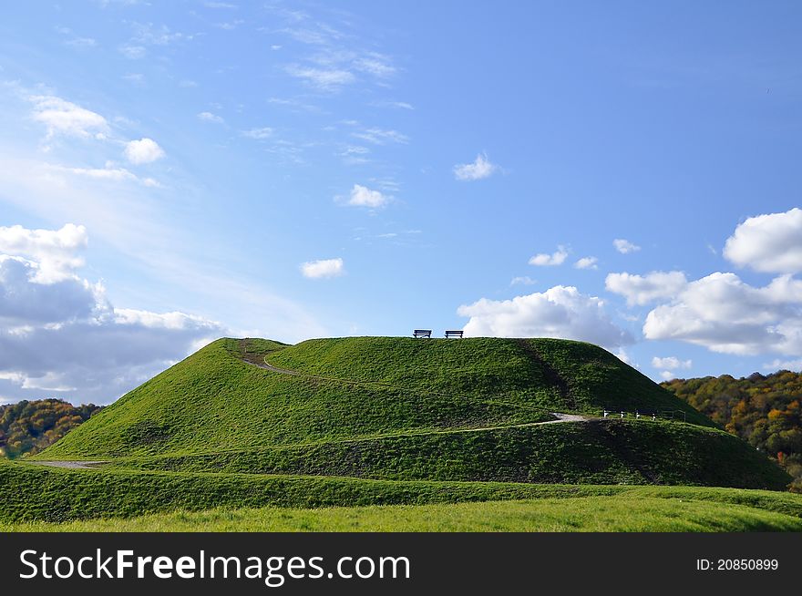 Green mound, hill, blue sky and clouds