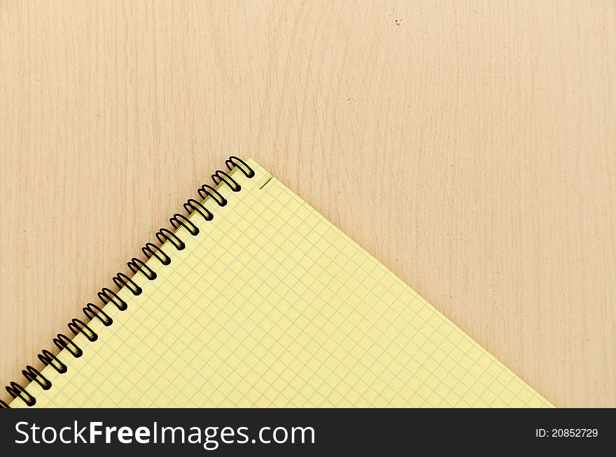 Yellow note book on wooden table background