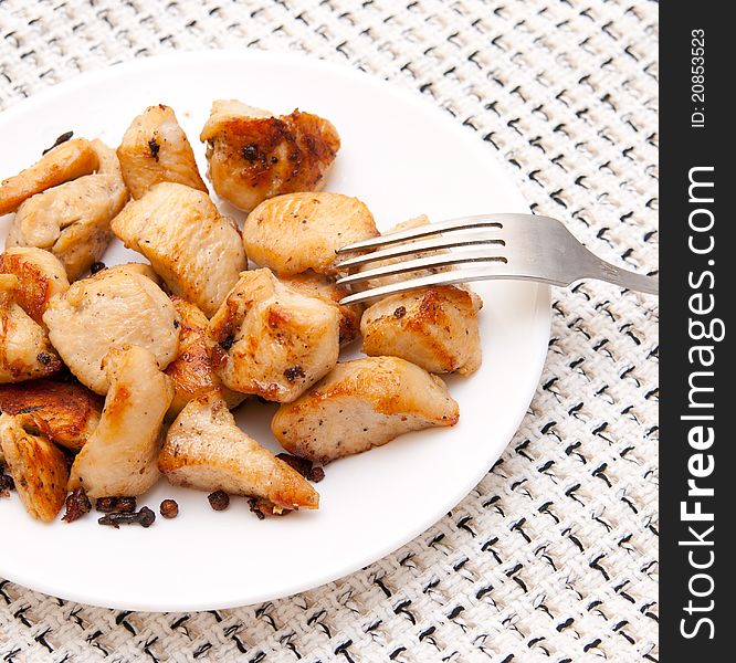 Many pieces of fried chicken well on a white plate with a fork on a checkered tablecloth. Many pieces of fried chicken well on a white plate with a fork on a checkered tablecloth