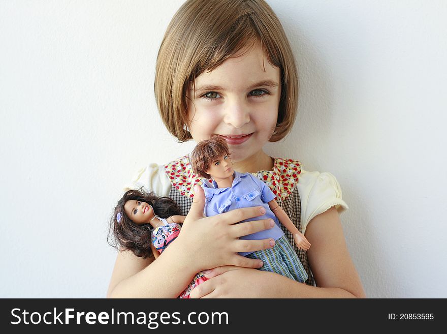 Little girl holding boy and girl dolls