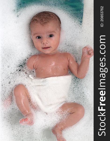 Cute baby girl bathing in soap bubbles