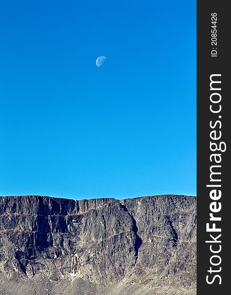 Moon on a background of blue sky and mountains