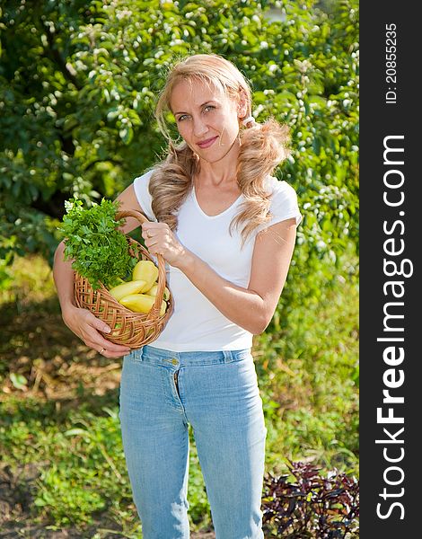 A Young woman holding vegetables in the garden