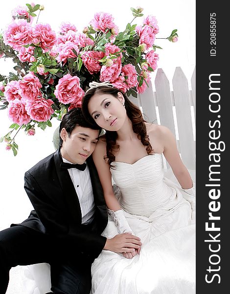 Portrait of young bride and groom sitting together with pink flower