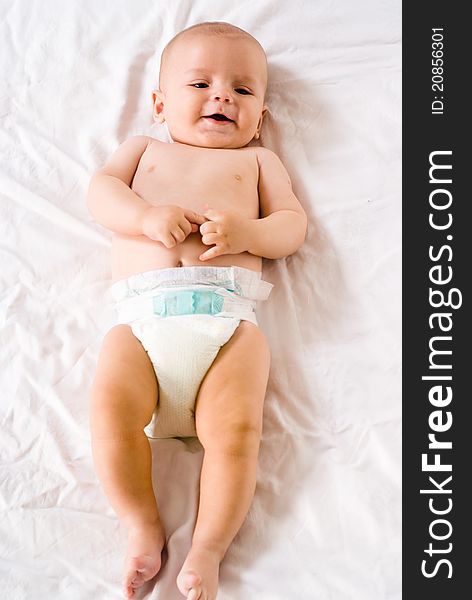 Portrait of a cute baby lying on bed on a white