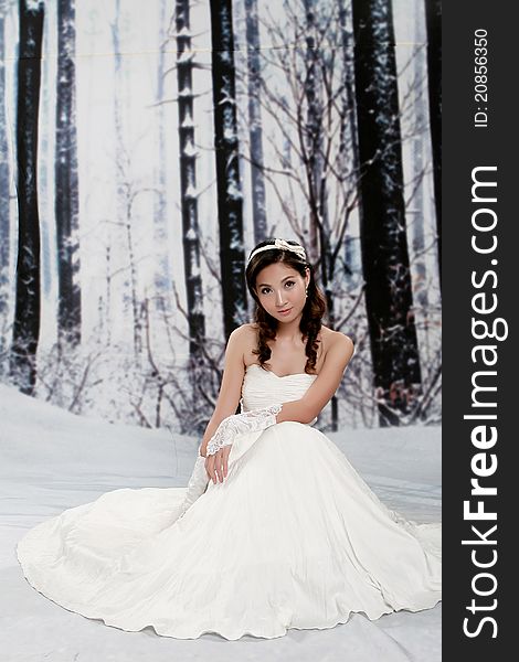 Portrait of beautiful young woman sitting in wedding dress