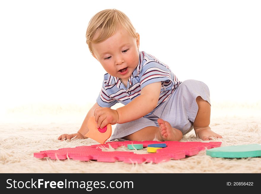 Little boy playing on a carpet on white